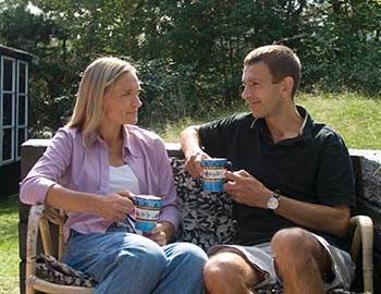 Par drikker kaffe i solen ved feriehuset
